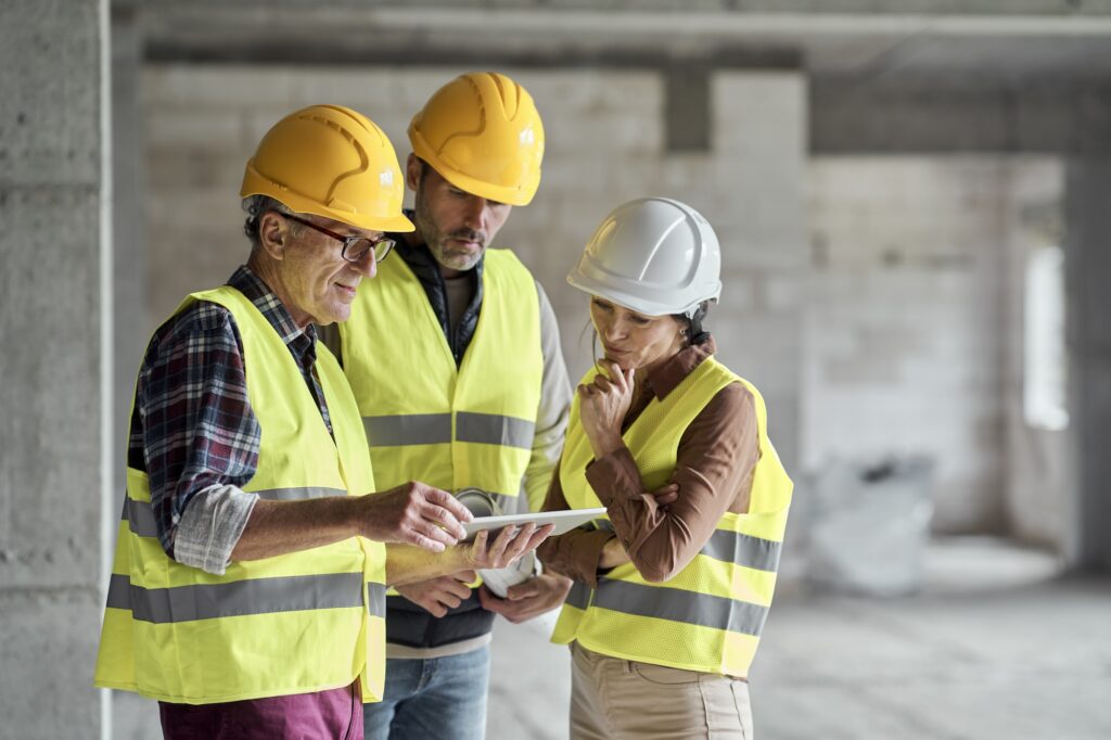 Drei Ingenieure besprechen Pläne auf einer Baustelle