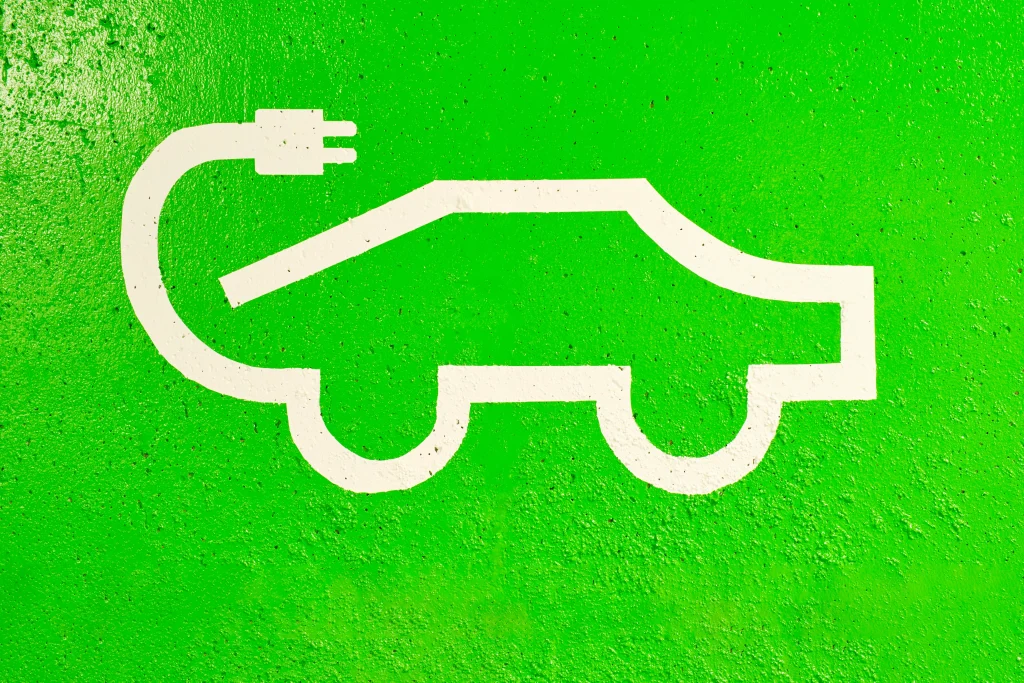Grünes Symbol eines Elektroautos mit Ladestecker – Vertron Systems beantwortet häufige Fragen zur Ladeinfrastruktur